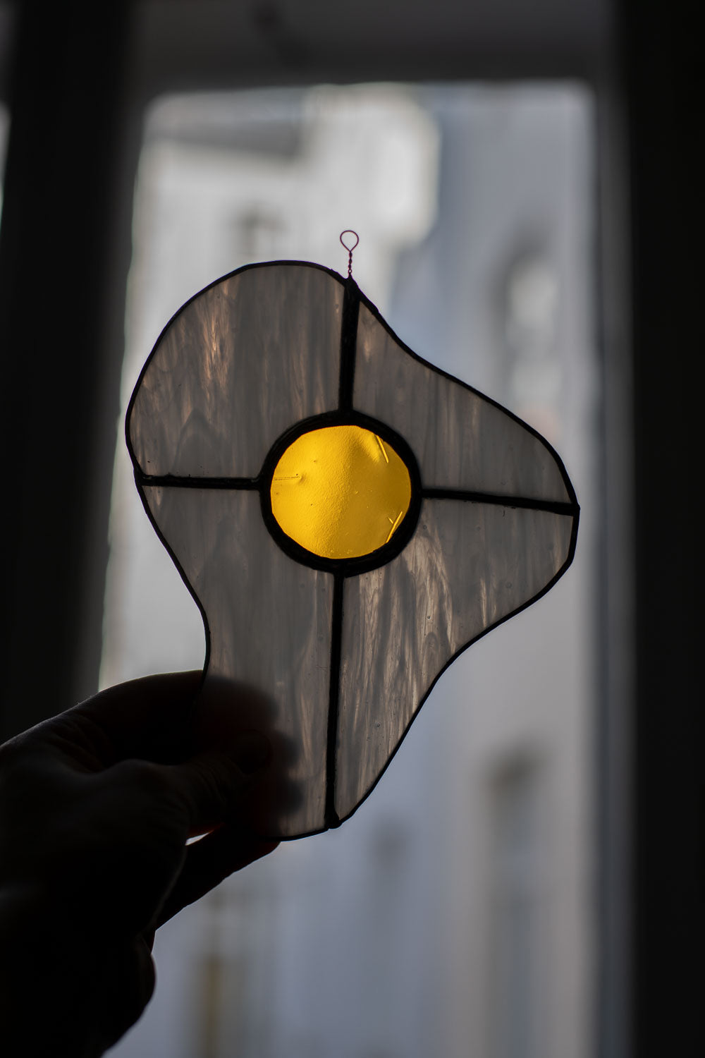 Egg-shaped stained glass piece held against a blurred background
