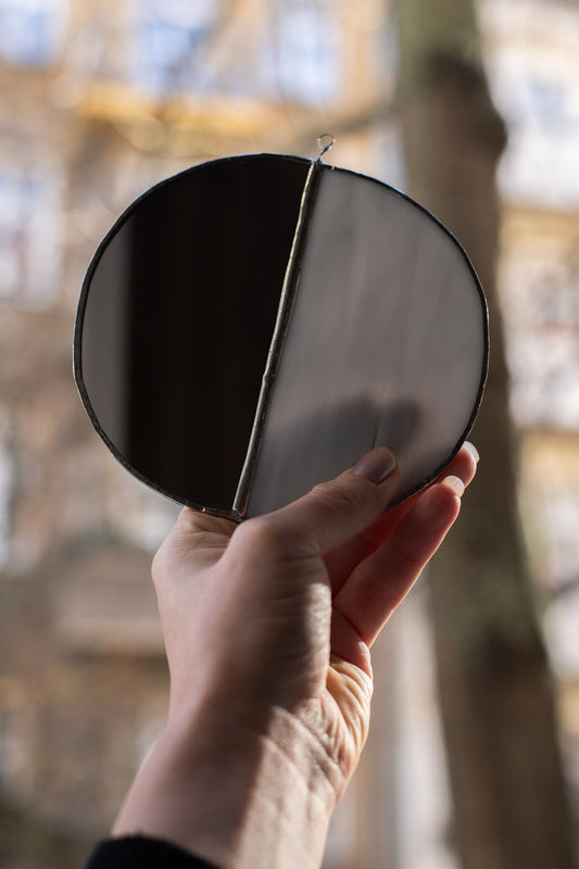 Hand holding a stained glass moon with a blurred background
