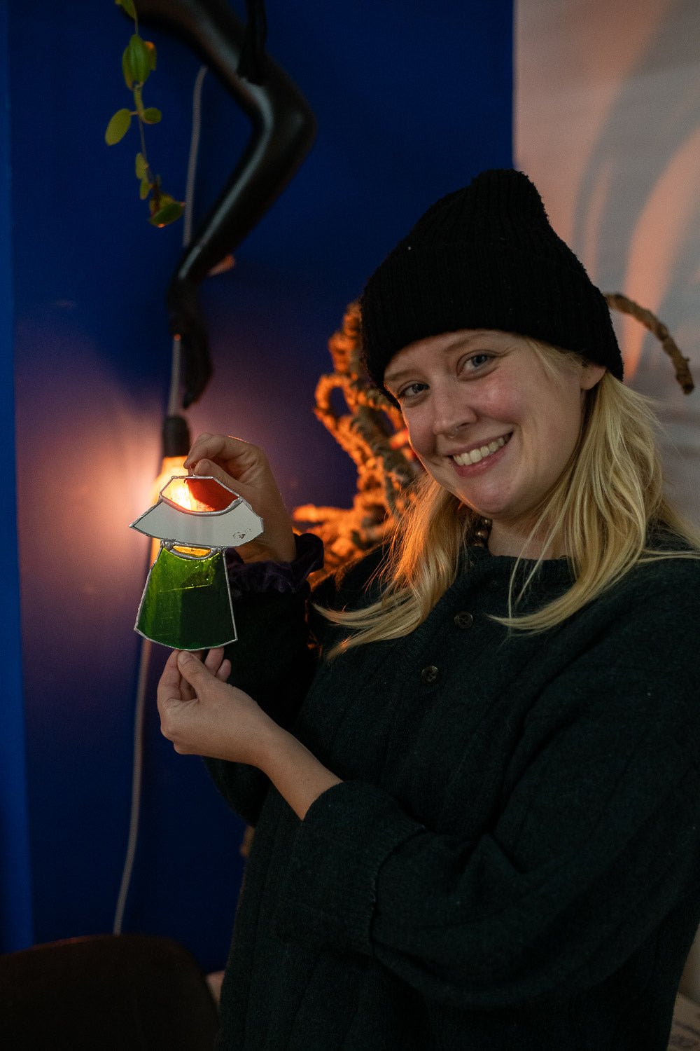 Someone happily holding a stained glass artwork in the shape of a UFO they made at the stained glass for beginners workshop