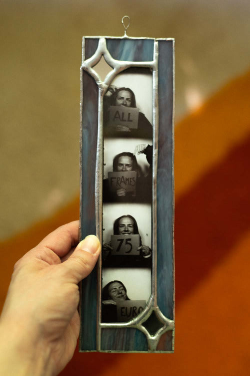 Hand holding a vertical photo frame with cut-out pictures of people holding signs.