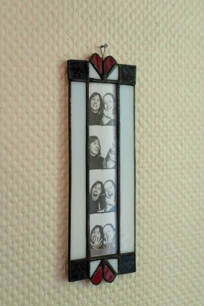 Stained glass photo frame with heart designs on a textured wall