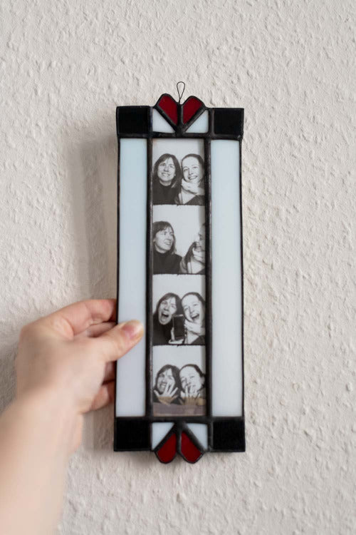 Stained glass photo frame with heart design held against a white wall