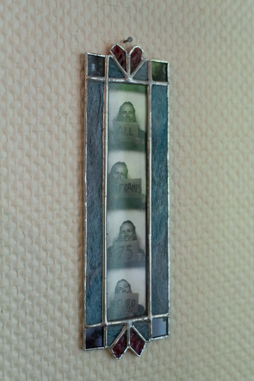 Decorative wall art with a blue frame and embedded photos on a textured beige wall.