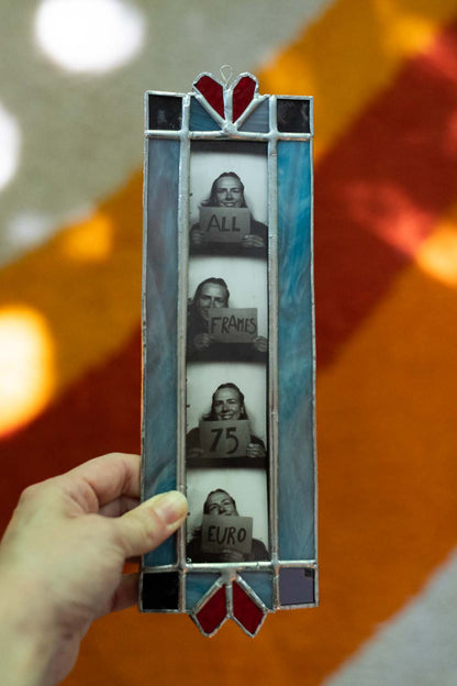 Stained glass picture frame held by a hand against a colorful background