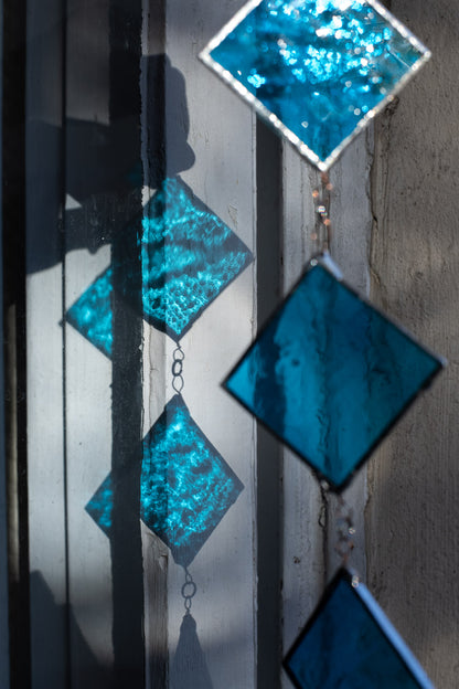 Decorative stained glass suncatcher with blue geometric shapes and their blue shadows